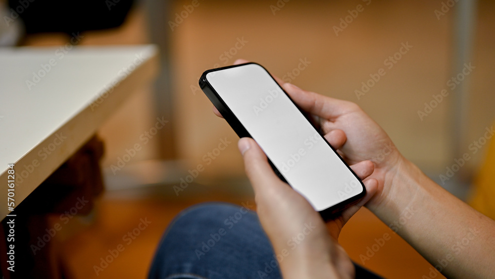 side view of a female holding a smartphone white screen mockup over blurred background. side view of a female holding a smartphone white screen mockup over blurred background.