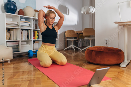 Woman is stretching tricepses after training at home