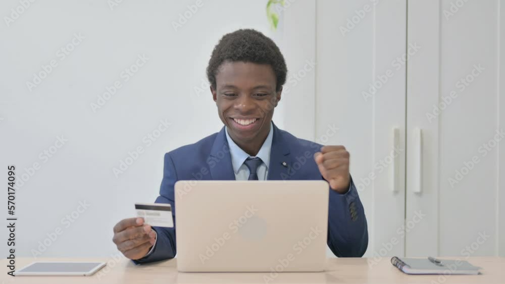 Young African Businessman Enjoying Successful Online Payment on Laptop Young African Businessman Enjoying Successful Online Payment on Laptop
