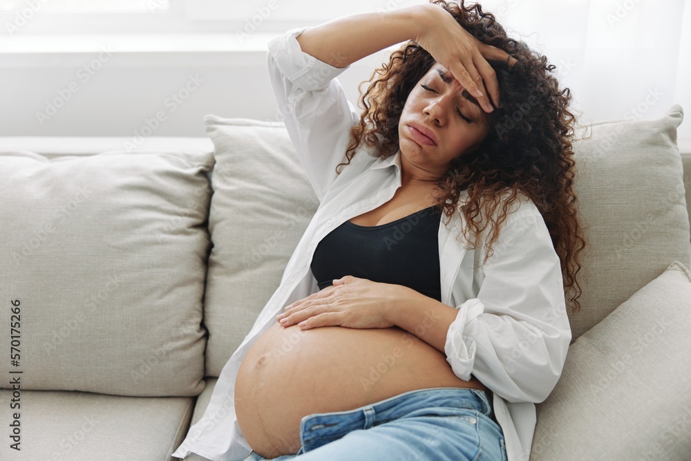Pregnant woman headache lies at home on the couch fatigue and heaviness in the last month of pregnancy before childbirth, motherhood difficulties, nausea