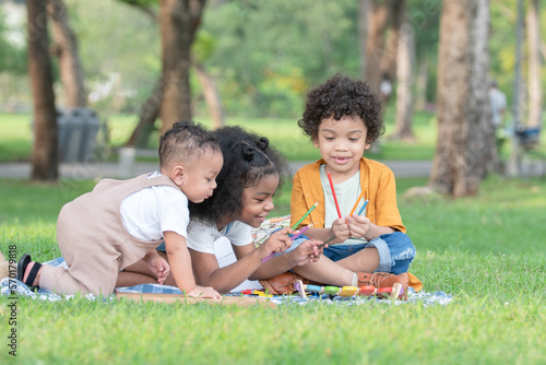 Little cute African children sitting and have fun playing xylophone making music sound while picnic at park together. Sibling relationship in family. Lifestyle and education concept