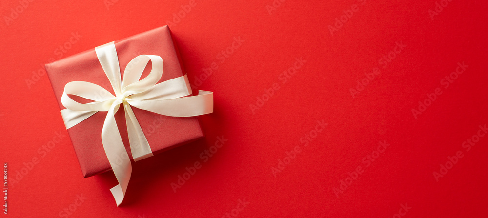 Saint Valentine's Day concept. Top view photo of giftbox with white ribbon bow on isolated red background with copyspace Saint Valentine's Day concept. Top view photo of giftbox with white ribbon bow on isolated red background with copyspace