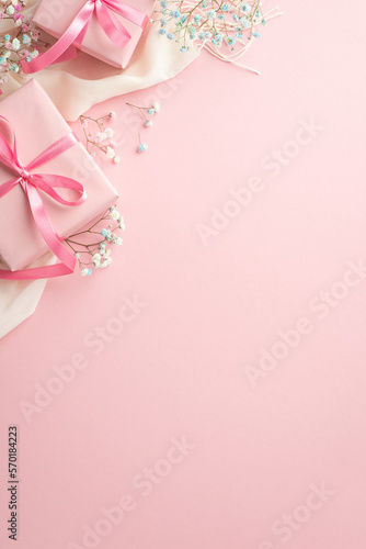 Spring mood concept. Top view vertical photo of pink gift boxes with ribbon bows white soft plaid and gypsophila flowers on isolated pastel pink background with blank space © ActionGP