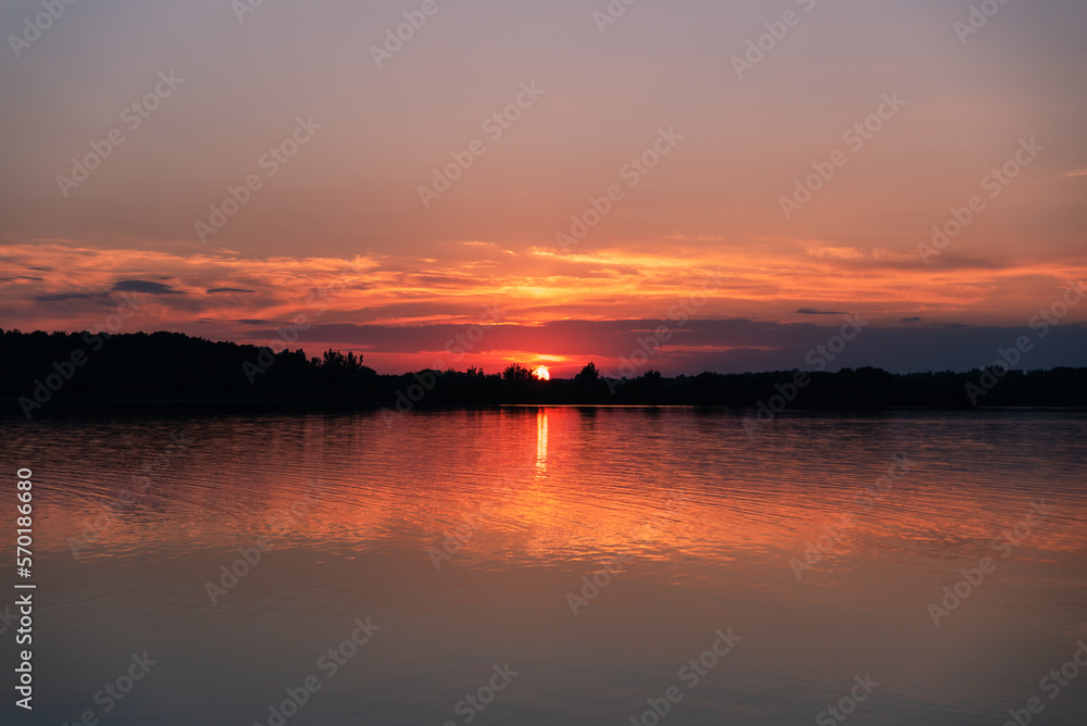 Sun setting behind the trees on horizon of a lake in Ontario, Canada. Sun setting behind the trees on horizon of a lake in Ontario, Canada.