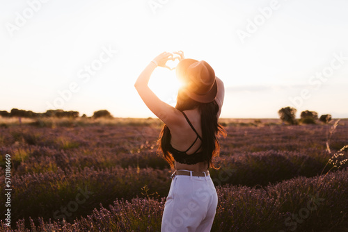 Woman forming a heart with her hands in a lavender field at sunset photo