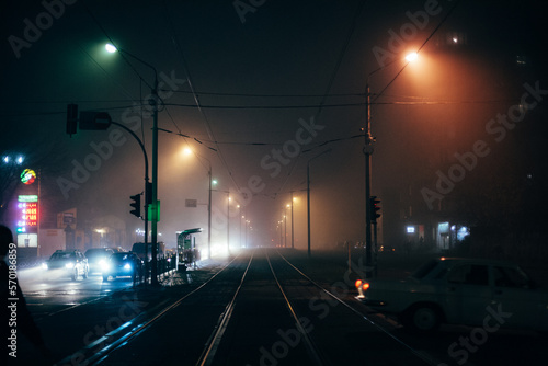 Foggy city street with tram ways during autumn at night photo