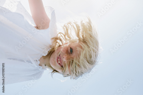 Child with blond hair looking at the camera from above photo