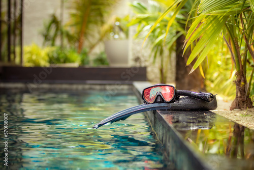 Swimming flippers and snorkeling mask laying on the edge of the pool