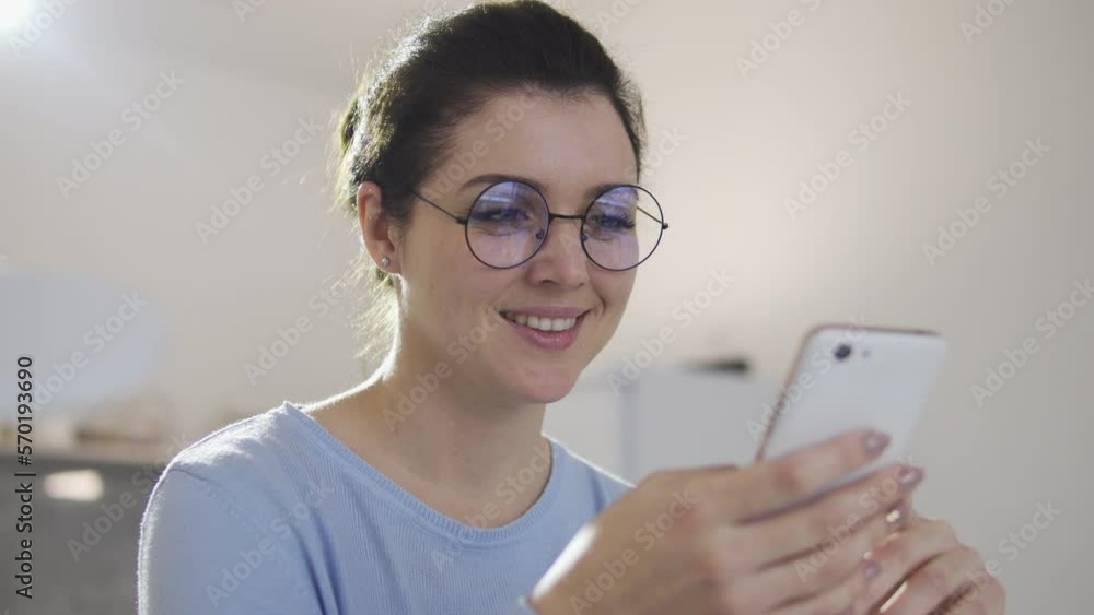 Happy young woman doing shopping online in smartphone, checking web stores with seasonal sales and discounts, booking stuff and ordering delivery to door Happy young woman doing shopping online in smartphone, checking web stores with seasonal sales and discounts, booking stuff and ordering delivery to door