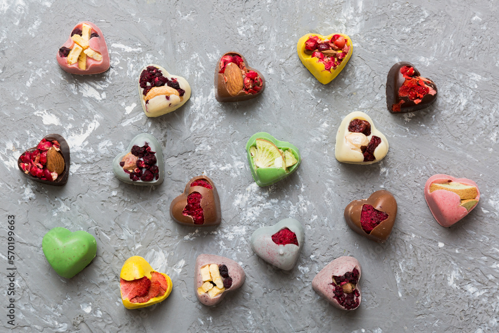 chocolate sweets in the form of a heart with fruits and nuts on a colored background. top view with space for text, holiday concept