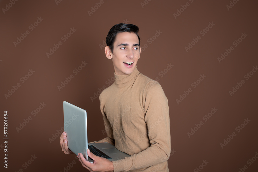 Funny young student with educational material in his hands. Emotions. Brown background. Funny young student with educational material in his hands. Emotions. Brown background.