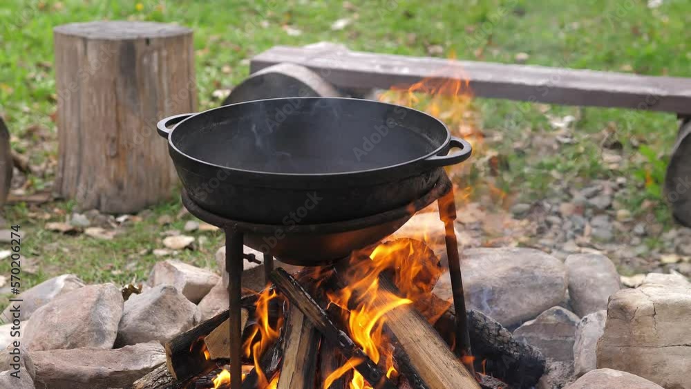 The meat is cut into pieces and built in oil in a cast iron cauldron. Cooking food outdoors in a cast iron cauldron on fire in camping. Cooking on campfire, picnic, camping. Preparation on open fire. The meat is cut into pieces and built in oil in a cast iron cauldron. Cooking food outdoors in a cast iron cauldron on fire in camping. Cooking on campfire, picnic, camping. Preparation on open fire.