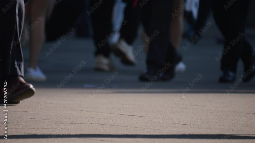 Legs of a crowd of people walking down the street, close-up of people's feet. Slow motion. Many feet walk on the pavement. Low view of crowded people walking in the square. Urban crowd. Legs of a crowd of people walking down the street, close-up of people's feet. Slow motion. Many feet walk on the pavement. Low view of crowded people walking in the square. Urban crowd.