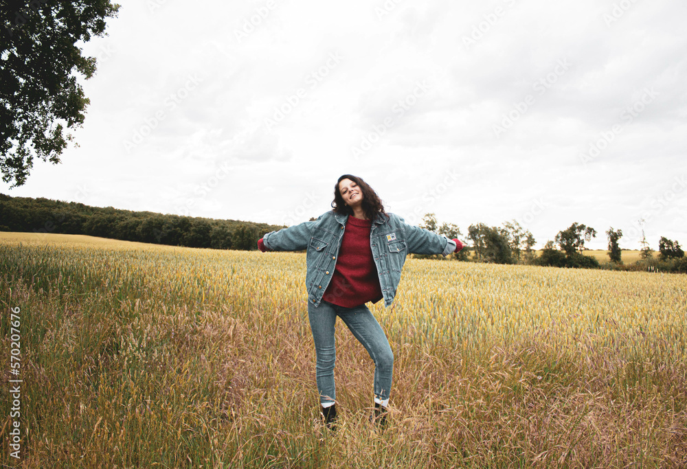 very happy young girl in the middle of the field against cloudy sky