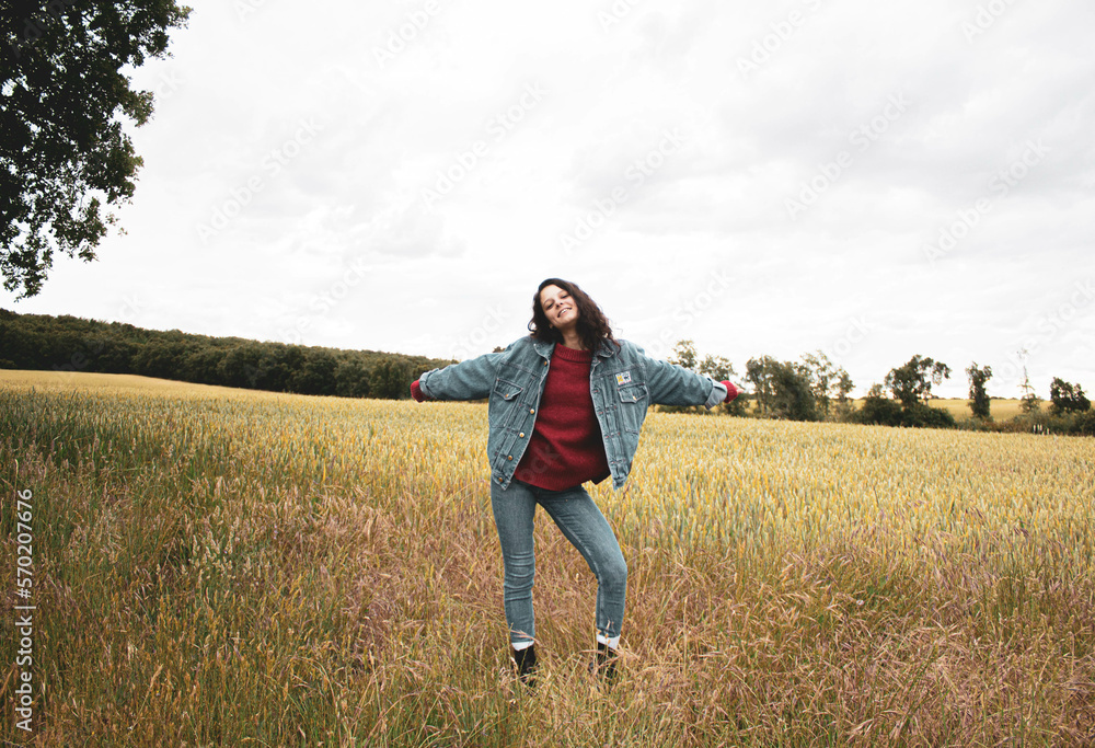 very happy young girl in the middle of the field against cloudy sky very happy young girl in the middle of the field against cloudy sky
