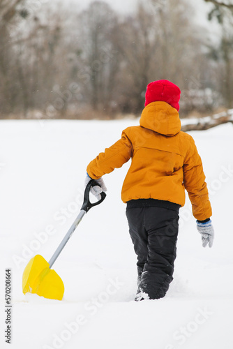 back view of boywith shovel in his hands on a snowy field. photo