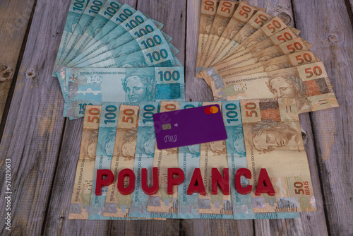 Rio Azul, Parana, Brazil - 04.09.2022: Credit card on banknotes of 50 and 100 reais, written in Portuguese in red 