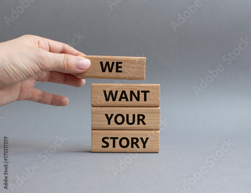We want your story symbol. Concept words We want your story on wooden blocks. Beautiful grey background. Businessman hand. Business and We want your story concept. Copy space.