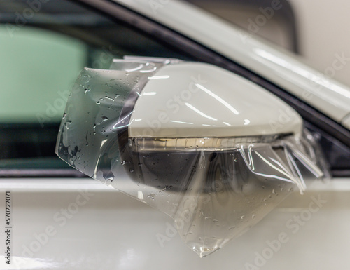 The process of installing PPF on the side mirror. PPF is a protective film for paint that protects the paint from scratches and gravel.Anti-gravity protection. PFF is installed. Car wrapping close-up. photo