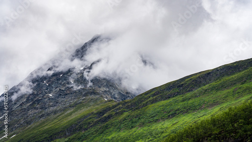 Misty mountain peak in Norway on an overcast day with green environment in the foreground