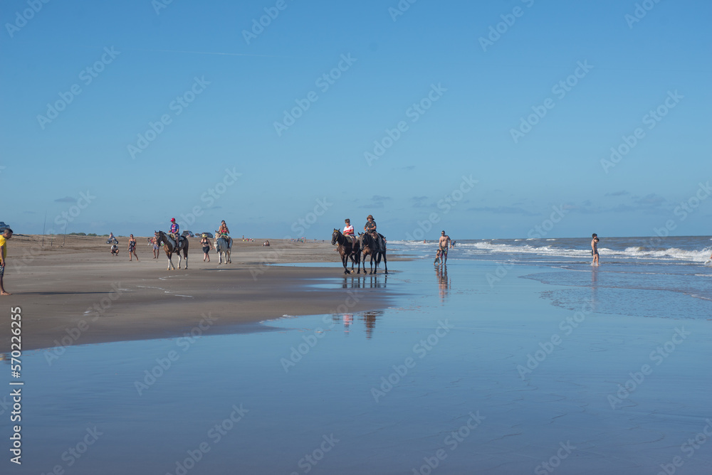 Grupo de adolescentes montando a caballo en la playa