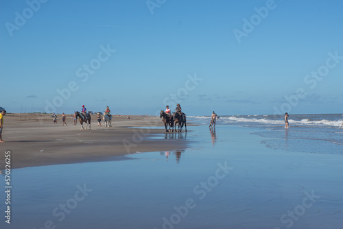 Grupo de adolescentes montando a caballo en la playa