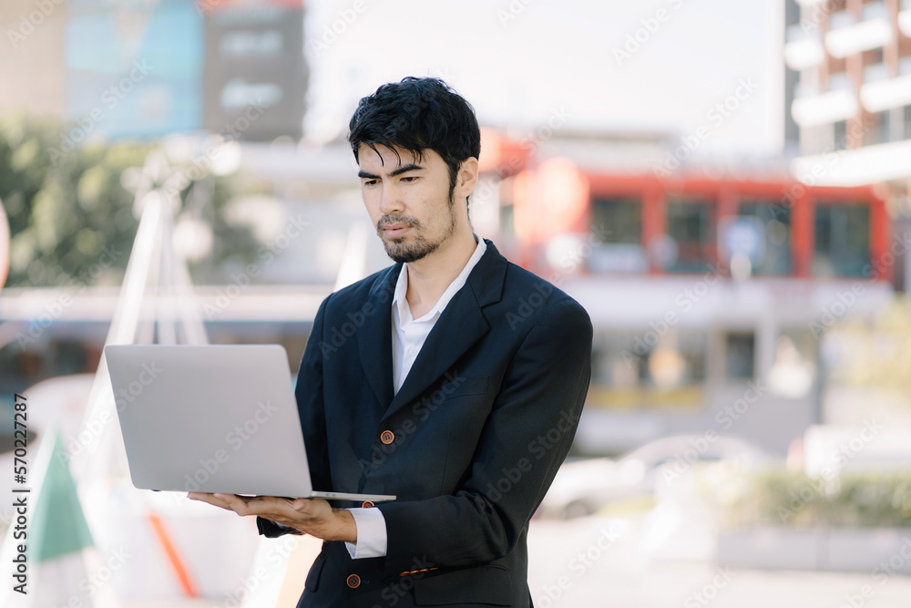 Portrait of Asian businessman holding laptop.Office worker at business center.