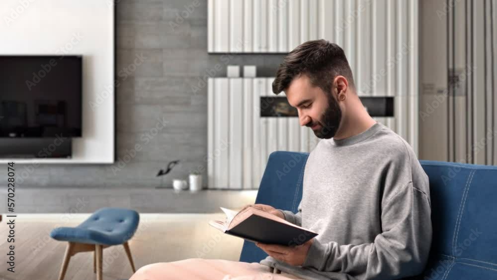 Smiling man reading paper book interesting literature on couch at home enjoy time for yourself Smiling man reading paper book interesting literature on couch at home enjoy time for yourself