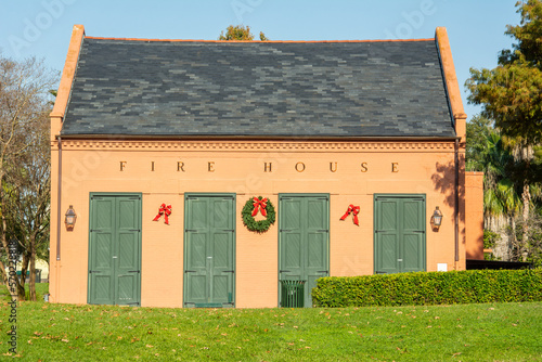 Red brick and green wooden doors of an old and abandoned fire house decorated for Christmas in Armstrong Park in New Orleans, Louisiana, USA photo