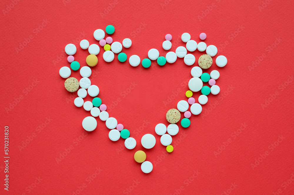 Many different tablets in shape of heart on red background. Medical flat lay . Valentine's Day.