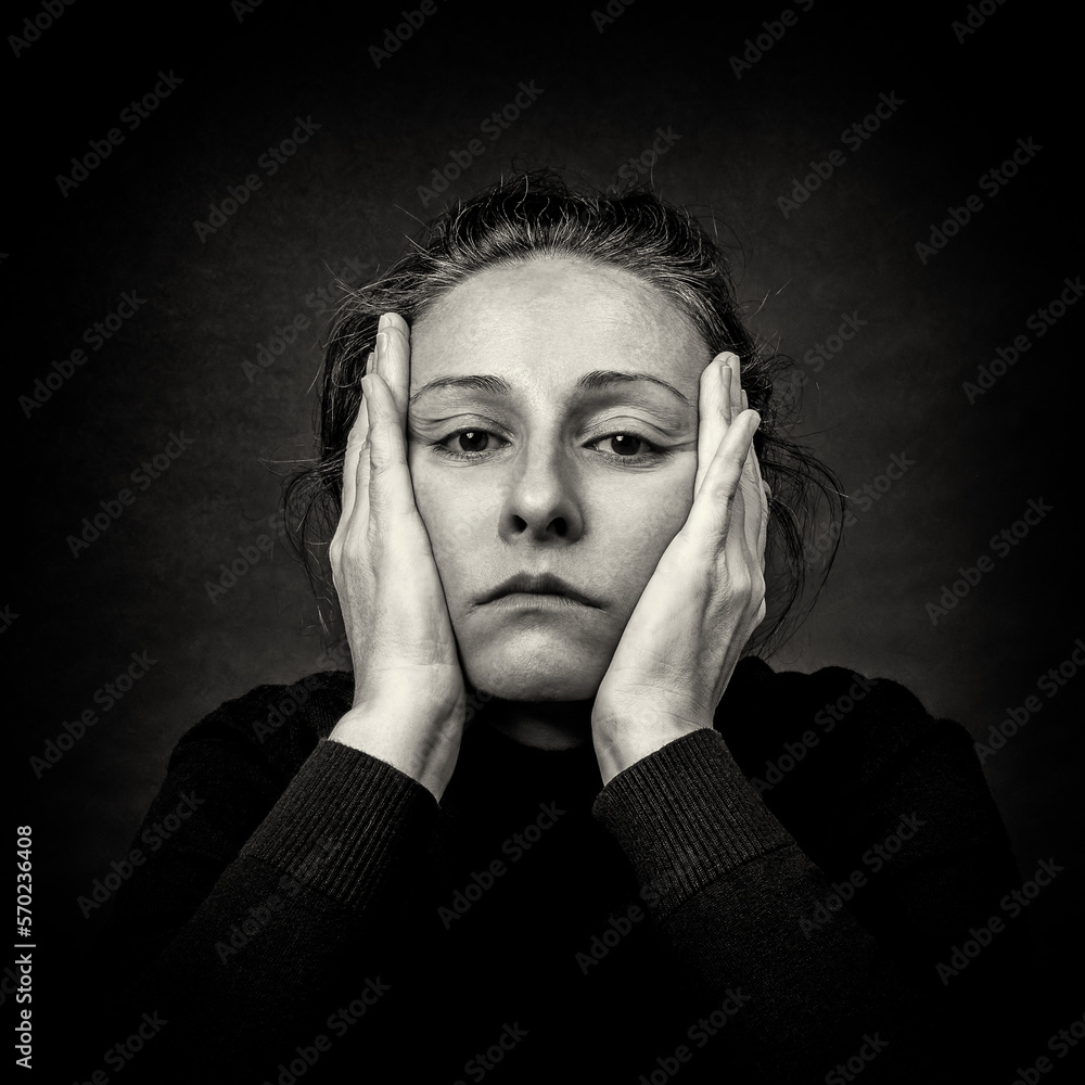 Conceptual dark portrait of pensive woman with hands over her head. Black and White film grain. Conceptual dark portrait of pensive woman with hands over her head. Black and White film grain.