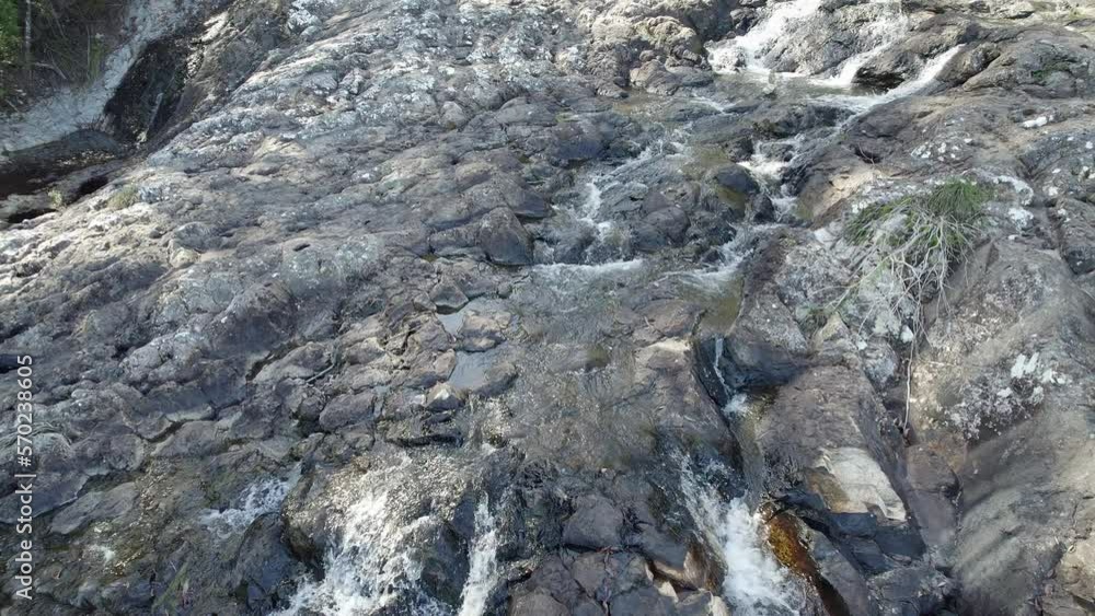 Minyon Falls - Stream Flowing On Rocks Towards Steep Cliff In The Northern Rivers Region, Australia. aerial pullback tilt-down reveal Minyon Falls - Stream Flowing On Rocks Towards Steep Cliff In The Northern Rivers Region, Australia. aerial pullback tilt-down reveal
