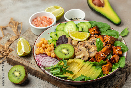 Baked tofu bowl with avocado, chickpeas, cucumber and mushrooms, buddha bowl. Vegan lunch salad, Food recipe background. Close up