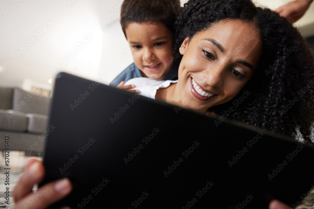 Love, mother with son on back and on floor with tablet, reading and learning together for quality time. Happy, mama and boy on ground, device and bonding on break, weekend and enjoy online videos