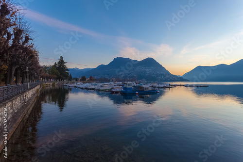Sunrise panorama of Lugano lake in autumn early morning with mooring for pleasure boats. Lugano, Ticino, Switzerland