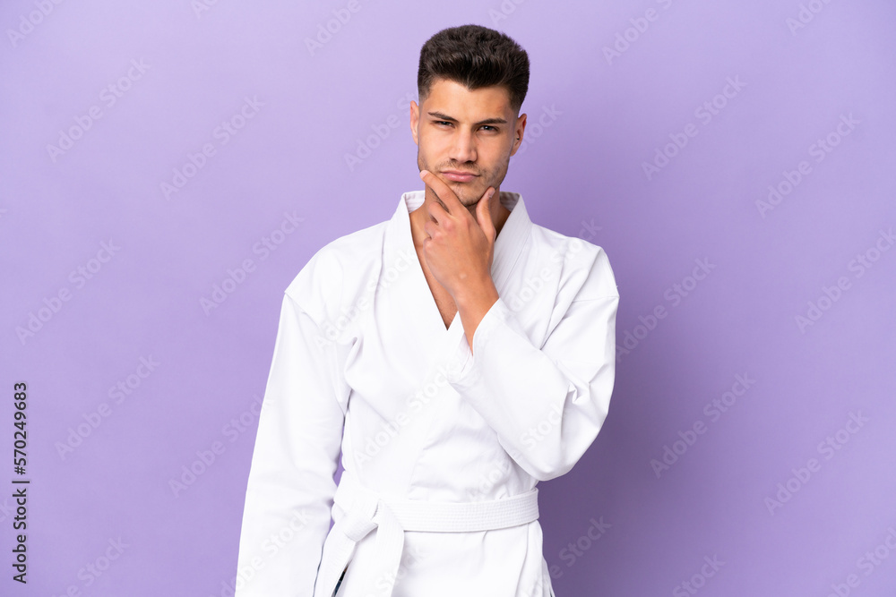 Young caucasian man doing karate isolated on purple background thinking Young caucasian man doing karate isolated on purple background thinking