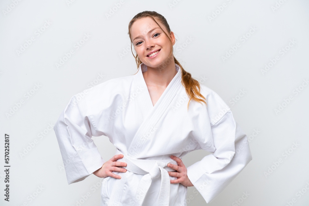 Young caucasian girl doing karate isolated on white background posing with arms at hip and smiling Young caucasian girl doing karate isolated on white background posing with arms at hip and smiling