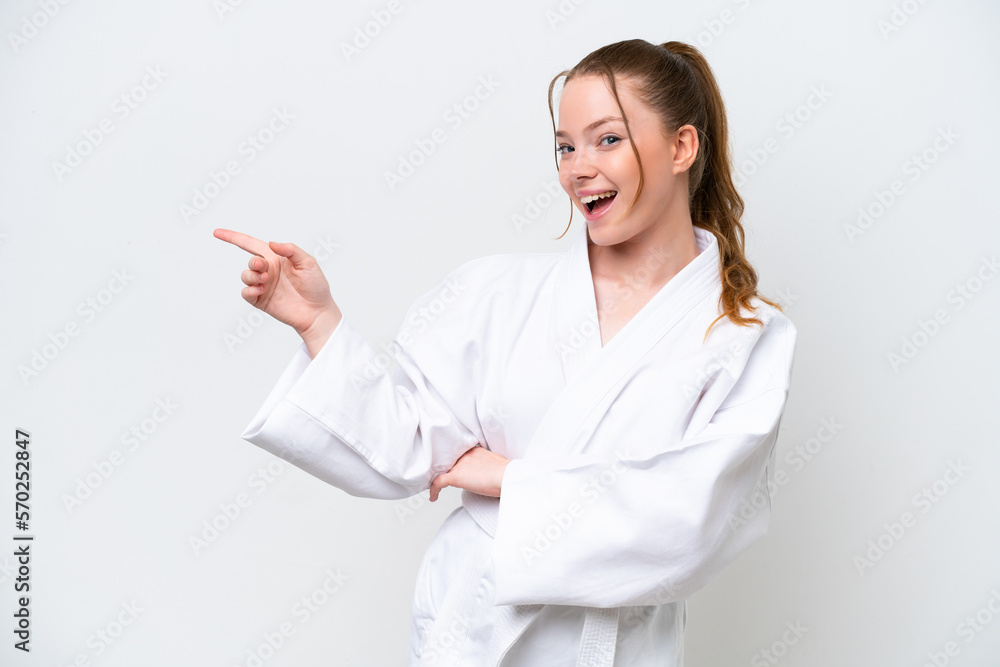 Young caucasian girl doing karate isolated on white background pointing finger to the side and presenting a product Young caucasian girl doing karate isolated on white background pointing finger to the side and presenting a product