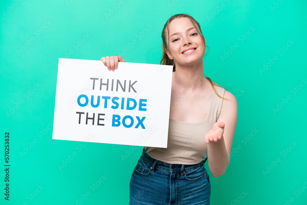 Young caucasian woman isolated on green background holding a placard with text Think Outside The Box making a deal Young caucasian woman isolated on green background holding a placard with text Think Outside The Box making a deal