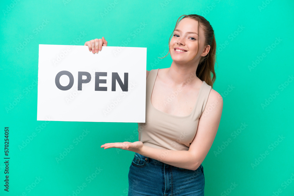 Young caucasian woman isolated on green background holding a placard with text OPEN with happy expression Young caucasian woman isolated on green background holding a placard with text OPEN with happy expression