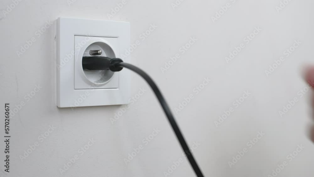 Male hand plugging and unplugging plug into white wall socket. Close-up power socket, caucasian man, charger cable Male hand plugging and unplugging plug into white wall socket. Close-up power socket, caucasian man, charger cable