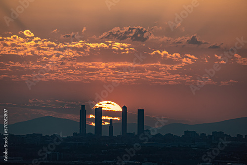 Orange sunset behind the Skyline and towers of the city of Madrid with buildings in silhouette