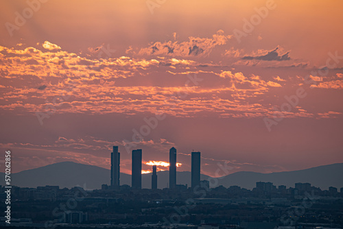 Orange sunset behind the Skyline and towers of the city of Madrid with buildings in silhouette