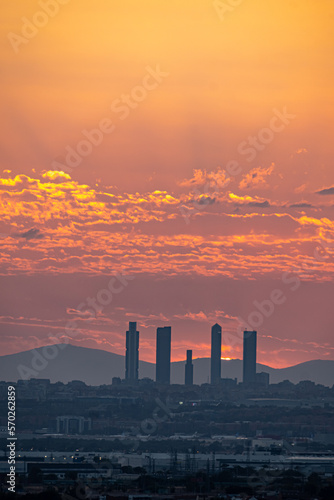 Orange sunset behind the Skyline and towers of the city of Madrid with buildings in silhouette