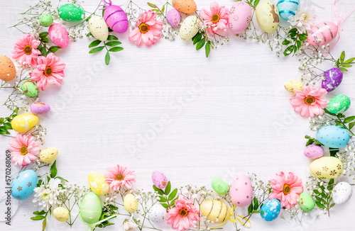 Spring Easter background with multicolored eggs and spring flowers on a wooden surface. Top view flat lay background . Greeting card pattern with copy space.