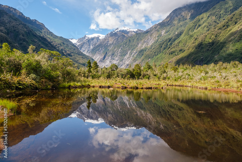 Peters Pool, a mirror lake, reflecting the snow capped mountains at Franz Josef on the South Island of New Zealand
