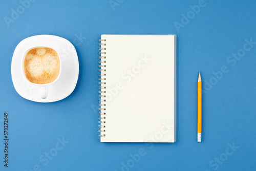 Open notepad with pencil and cup of coffee.