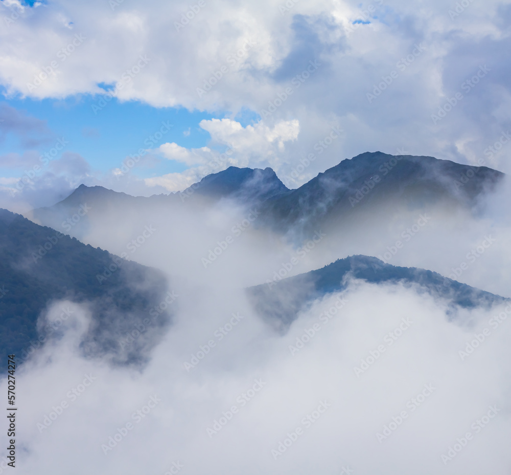 mountain ridge silhouette in dense mist and clouds, natural mountain travel background