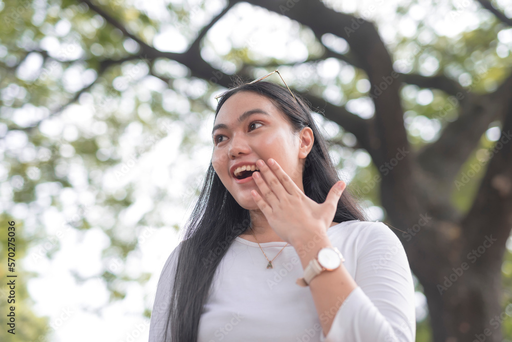 A lovely young lady looks sideways while holding her hand in front of her mouth with a shocked facial expression. A lovely young lady looks sideways while holding her hand in front of her mouth with a shocked facial expression.