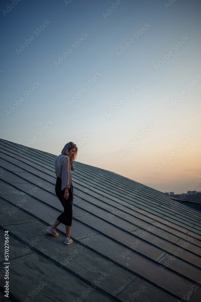 Young woman in the roof enjoying sunset, freedom city atmosphere. People, lifestyle, relaxation concept.